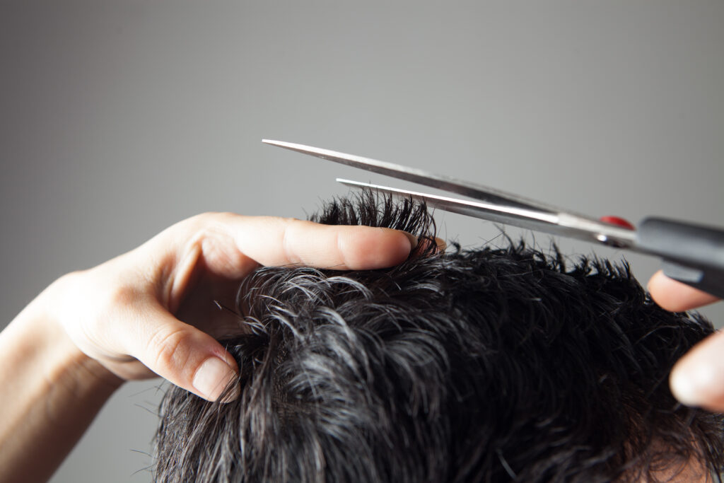 barber cuts hair men with scissors